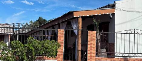A residential building with a brick facade, a metal gate, and a covered porch.