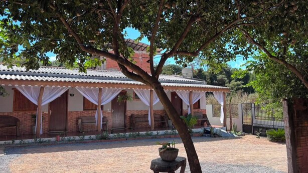 A building with a tiled roof, brick walls, and a covered porch with white curtains.