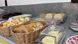 Uma mesa de buffet com diversos alimentos, incluindo pão, manteiga e queijo.