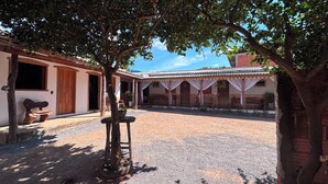 A courtyard with a building featuring a tiled roof and a covered seating area. - POUSADA MOAÇARA (Nobres)