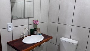 A bathroom with a wooden vanity, white sink, mirror, and white toilet.