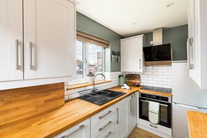 Eine moderne Küche mit weißen Schränken, einer Holz Arbeitsplatte, einem eingebauten Backofen und einer Edelstahl-Dunstabzugshaube.