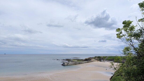 A coastal beach with a rocky shoreline, a small structure near the water, and a person walking on the sand. - Cullercoats Coastal Escape - 3 bedroom Modern Home - Pass the Keys (Newcastle)