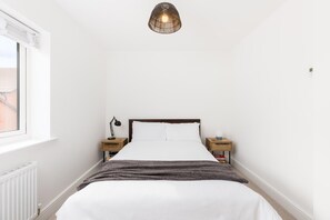 A bedroom with a bed, bedside tables, a lamp, a radiator, and a window. - 2 Bed Modern Terrace, Leamington Spa - Pass the Keys (Leamington Spa)
