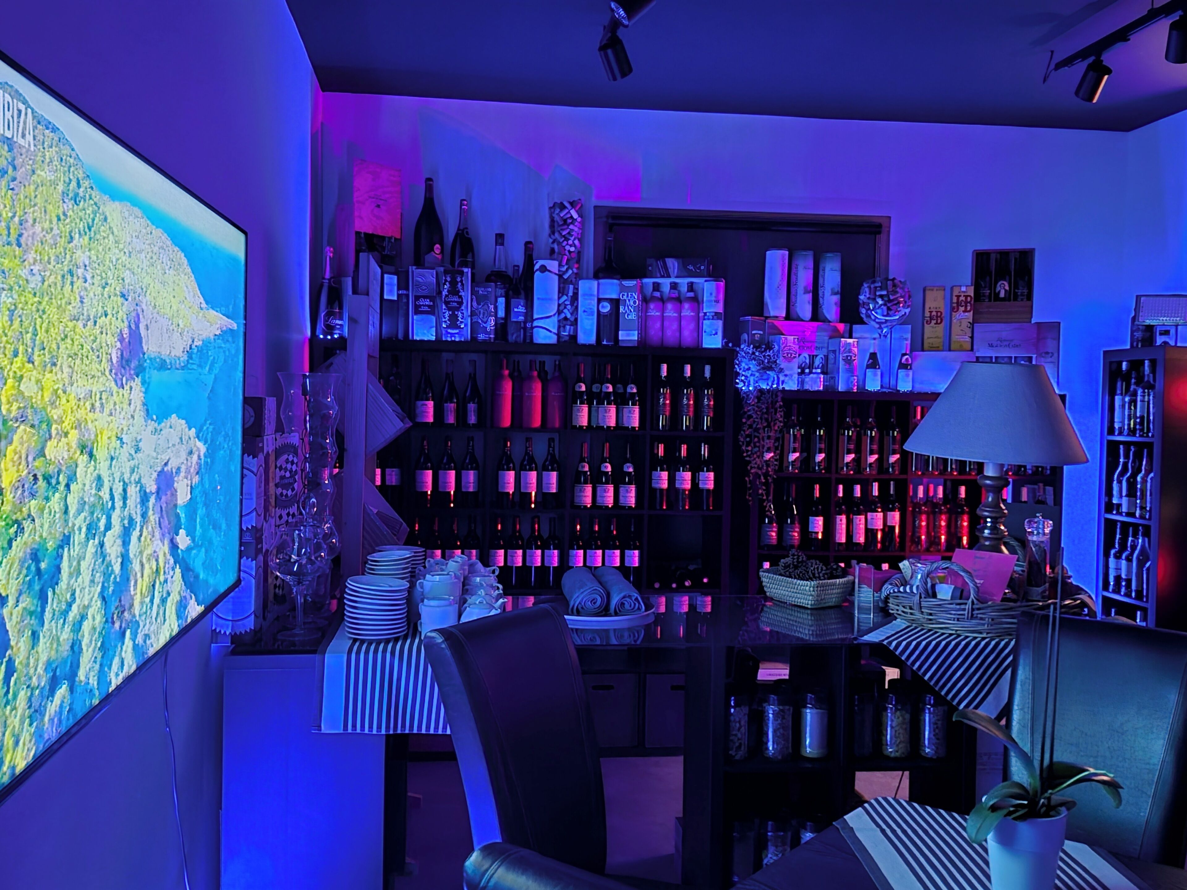 A bar area with shelves of bottles, a map on the wall, and a table with chairs.