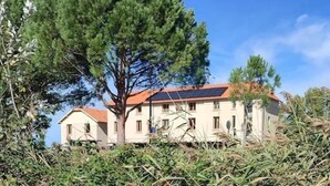 A building with a red roof, surrounded by greenery and trees. - Les Logis du Port Canal Suites & Spas  (Montauban)