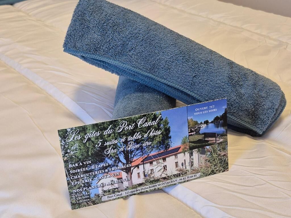 Une serviette bleue pliée et une carte de visite sur un lit.
