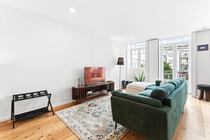 Un salon avec un canapé, un téléviseur et une petite table sur laquelle sont posés des livres.