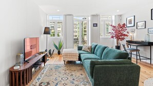 Una sala de estar moderna con un sofá, televisor y un comedor con una mesa y sillas.