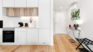 Una cocina moderna con armarios blancos, horno empotrado y cafetera.