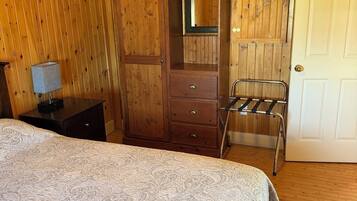 Een kamer met houten lambrisering, een bed, een kledingkast, een spiegel en een deur.