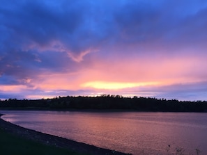 A calm lake at sunset with a forested shoreline.