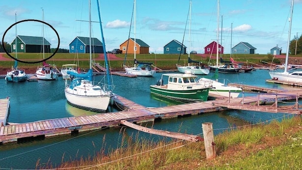 Un port de plaisance avec des bateaux amarrés, des quais en bois et plusieurs petits bâtiments en arrière-plan.