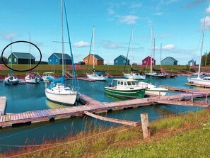 A marina with boats docked, wooden docks, and several small buildings in the background.