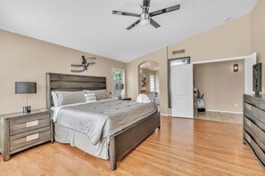 A bedroom with a bed, nightstands, a ceiling fan, and a wooden floor. - Spacious Home in a Central Location w/ Private Pool & Fire Pit (Gilbert)