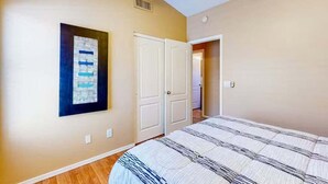 A bedroom with a bed, a door, and a wall-mounted artwork. - Spacious Home in a Central Location w/ Private Pool & Fire Pit (Gilbert)