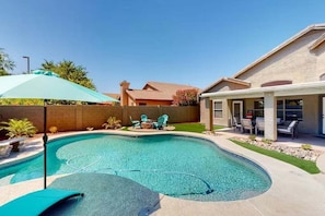 Ein Garten mit Swimmingpool, Terrassenmöbeln und einer überdachten Sitzgelegenheit.