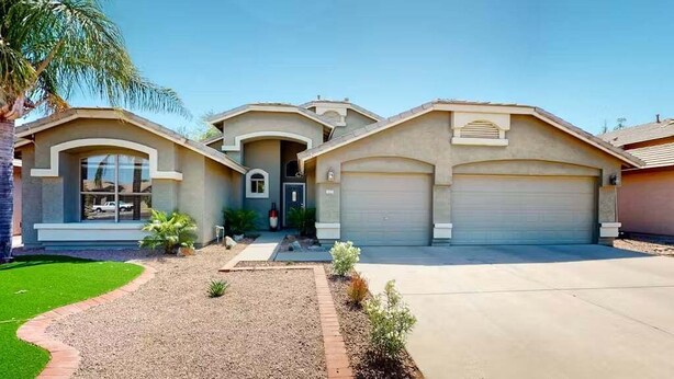 A two-story house with a garage, a driveway, and a well-maintained lawn. - Spacious Home in a Central Location w/ Private Pool & Fire Pit (Gilbert)
