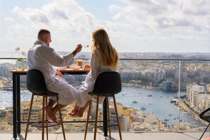Ein Paar genießt das Essen an einem Tisch mit Blick auf die Stadt.