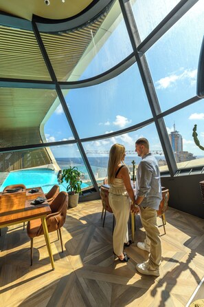 Ein modernes Interieur mit einem großen Panoramafenster, einem Pool und einem Essbereich.