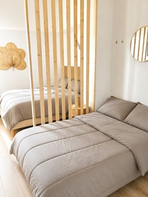 A bedroom with a bed, a wooden partition, a round mirror, and a wall-mounted decorative leaf. - LVAM - Duplex Apartment for 4 Guests - In the Heart of Cap d'Agde - Pool (Le Cap D'Agde)