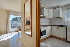 Eine moderne Küche mit weißen Schränken, einem eingebauten Backofen und einem Essbereich mit Stuhl und Tisch.
