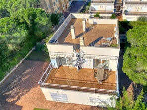 Ein mehrstöckiges Gebäude mit Dachterrasse, einer Treppe und einem Poolbereich.