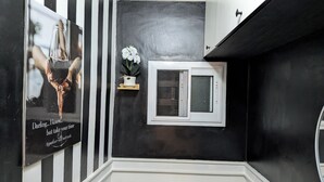 A black and white striped wall, a small window with a view, and a framed picture with text.
