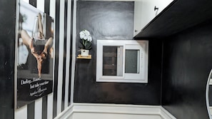A black and white striped wall, a small window with a view, and a framed picture with text.