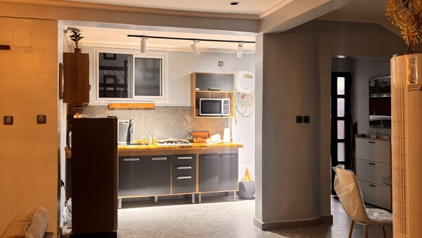 A modern kitchen with a refrigerator, microwave, and wooden cabinets.