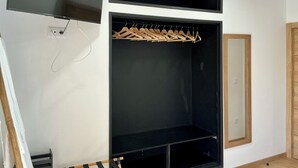 Una habitación con un armario negro, un espejo y un televisor colocado en la pared.