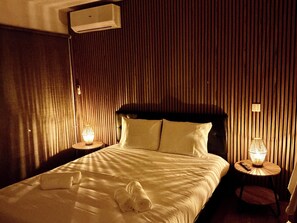 Ein Hotelzimmer mit einem Bett, zwei Nachttischlampen, einer Wand-Klimaanlage und einem Sessel.