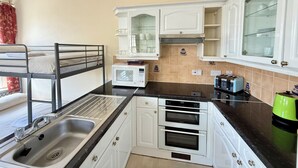Eine kleine Küche mit Spüle, Mikrowelle, Toaster und Backofen.
