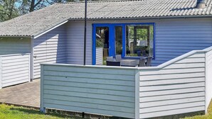 Una casa pequeña con puerta azul y un patio cubierto.
