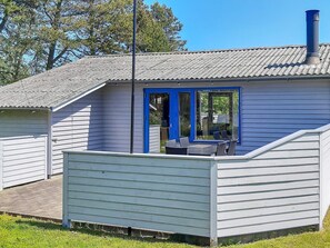 A small house with a blue door and a covered patio area. - 4 Person Holiday Home in Saeby (Sæby)