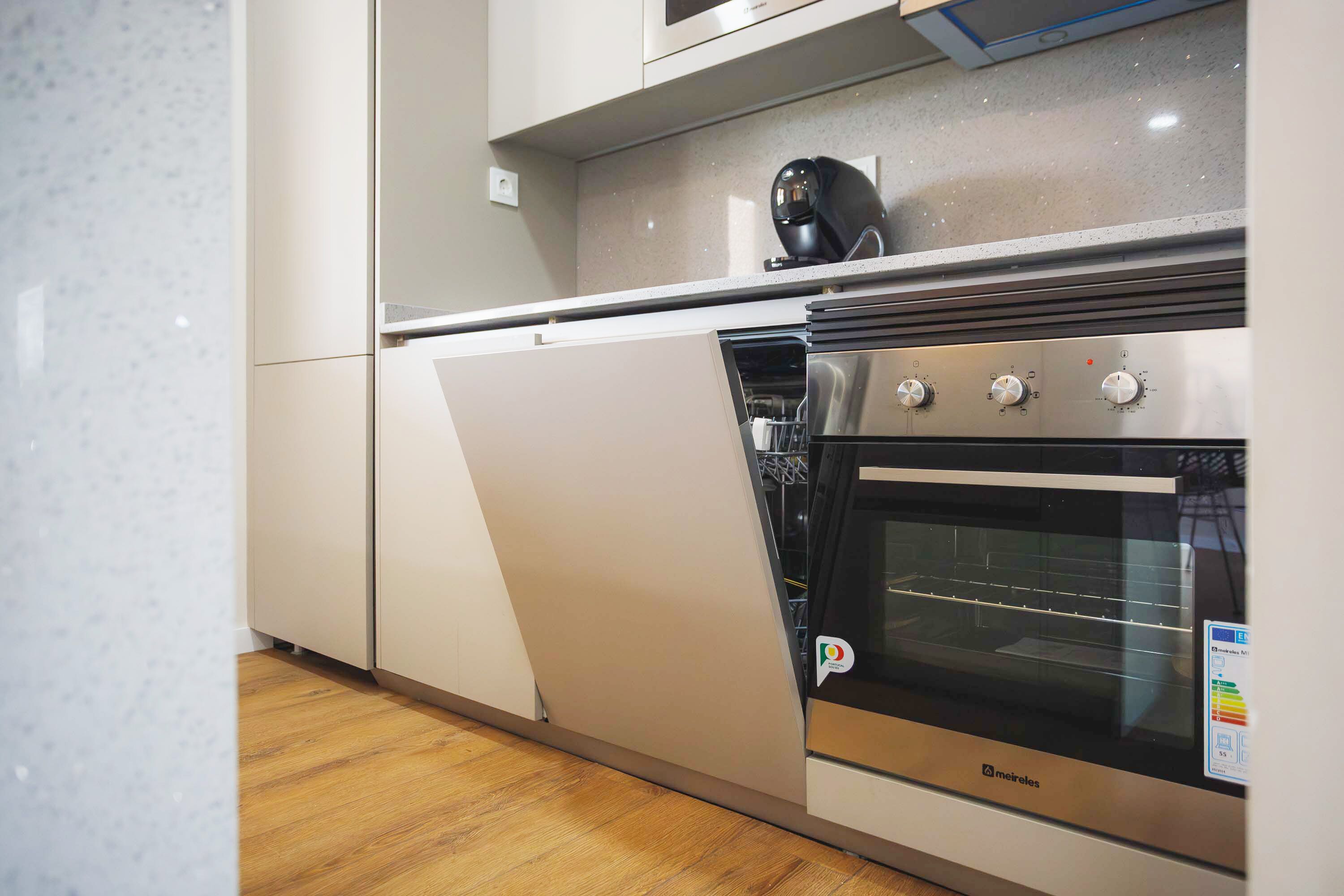 A kitchen with a built-in oven, a coffee machine, and a stainless steel range hood.