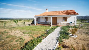 A single-story house with a tiled roof, a paved driveway, and a small garden area.