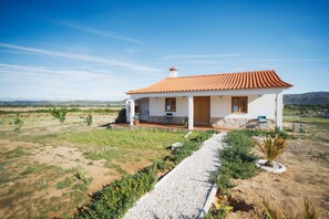 A single-story house with a tiled roof, a paved driveway, and a small garden area.