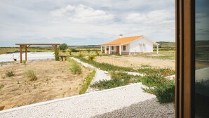 A white house with a tiled roof, a gravel pathway, and a wooden pergola.