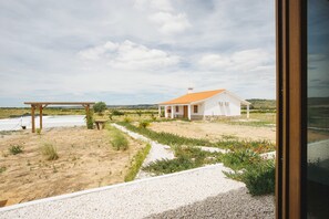 A white house with a tiled roof, a gravel pathway, and a wooden pergola.