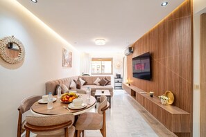 Ein modernes Wohnzimmer mit Essbereich, einem an der Wand montierten Fernseher und einer gemütlichen Sitzecke.