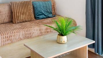 A living room with a sofa, a small table, and a potted plant.