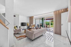 A modern living room with a sofa, coffee table, TV, and a sliding glass door leading to an outdoor patio. - Apartamento Kelle | 2 bedrooms | Villa Sol | Quarteira (Quarteira)