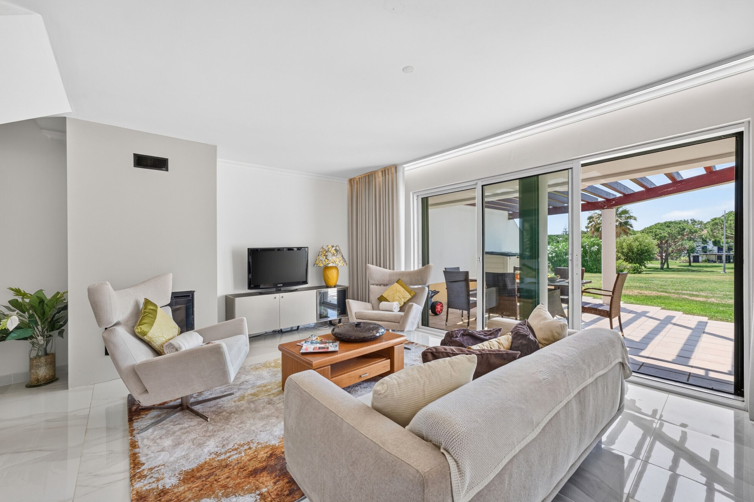 A modern living room with a sofa, armchairs, a coffee table, and a TV.