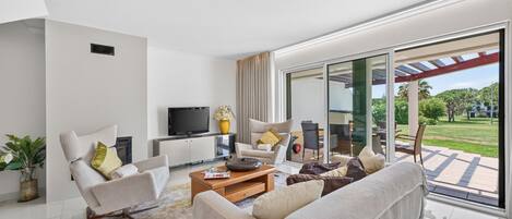 A modern living room with a sofa, armchairs, a coffee table, and a TV.