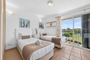 Ein Hotelzimmer mit zwei Betten, einem Balkon mit Blick und Bildern an den Wänden.