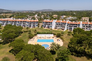 Ein Resort mit mehreren Gebäuden, einem Swimmingpool und umgebender Vegetation.