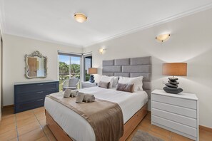 A bedroom with a large bed, bedside tables, a dresser, a mirror, and a balcony view. - Apartamento Kelle | 2 bedrooms | Villa Sol | Quarteira (Quarteira)