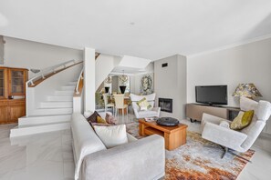 A modern living room with a staircase, a flat-screen TV, and a dining area. - Apartamento Kelle | 2 bedrooms | Villa Sol | Quarteira (Quarteira)