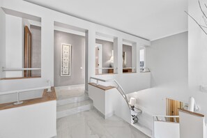Ein modernes Badezimmer mit Marmorboden, einer Holzbank und einem weißen Waschbecken.